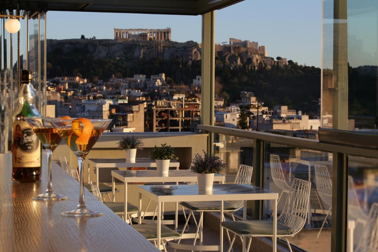 een balkon met tafels en stoelen en uitzicht op de stad bij Evripides Hotel in Athene