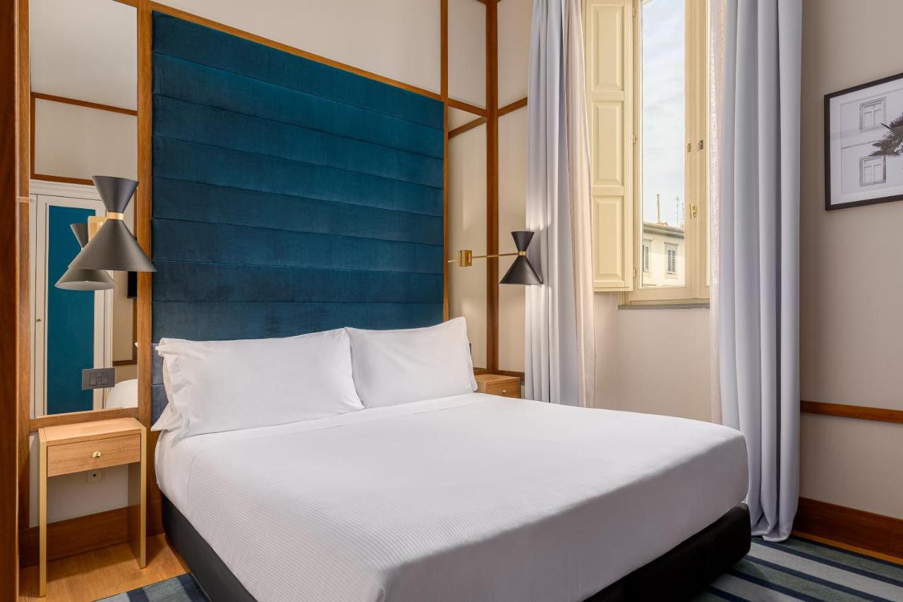 een slaapkamer met een groot bed en een blauw hoofdbord bij Room Mate Luca, Florence in Florence