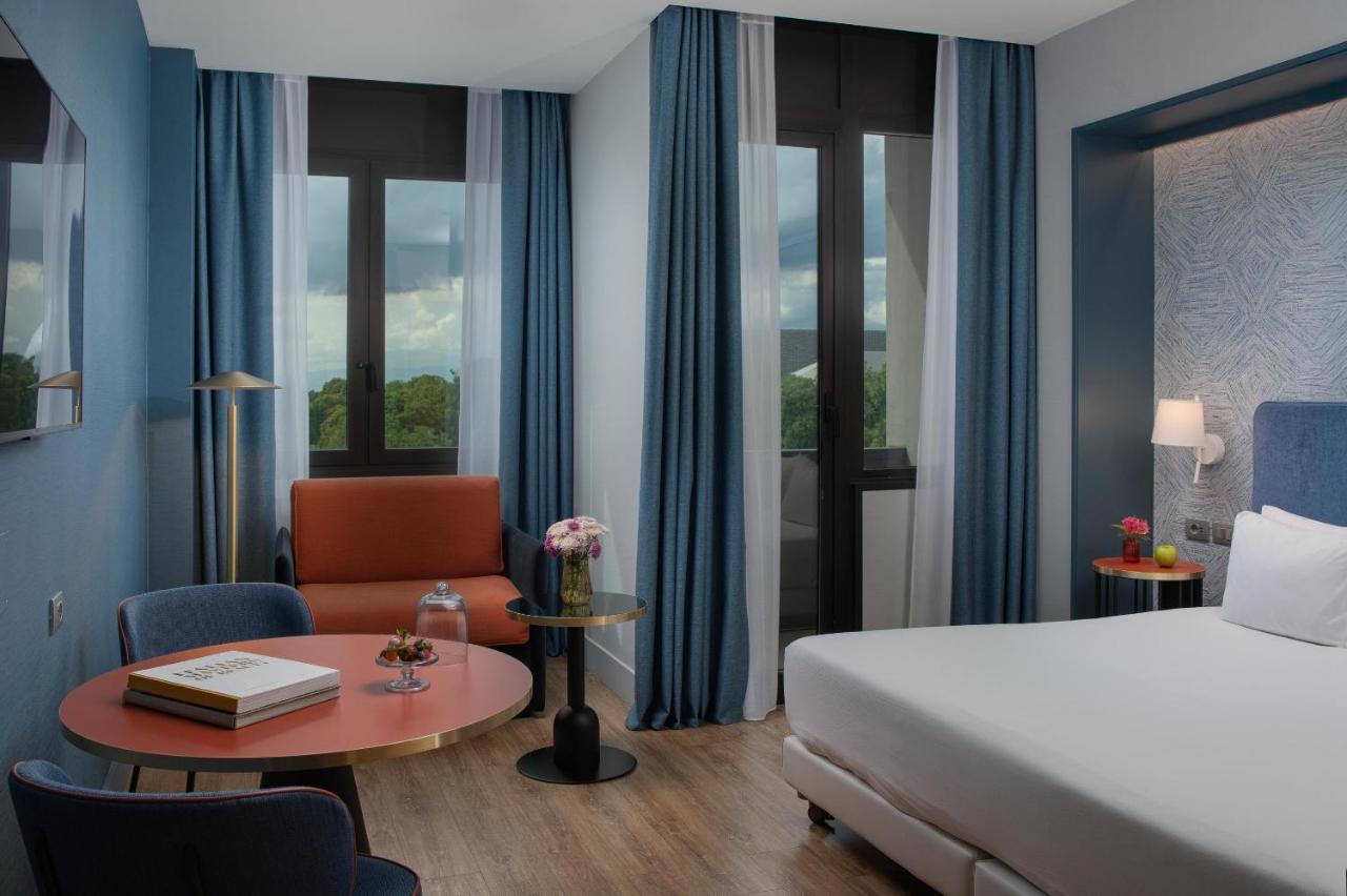 een hotelkamer met een bed, een stoel en een tafel bij NH Firenze in Florence