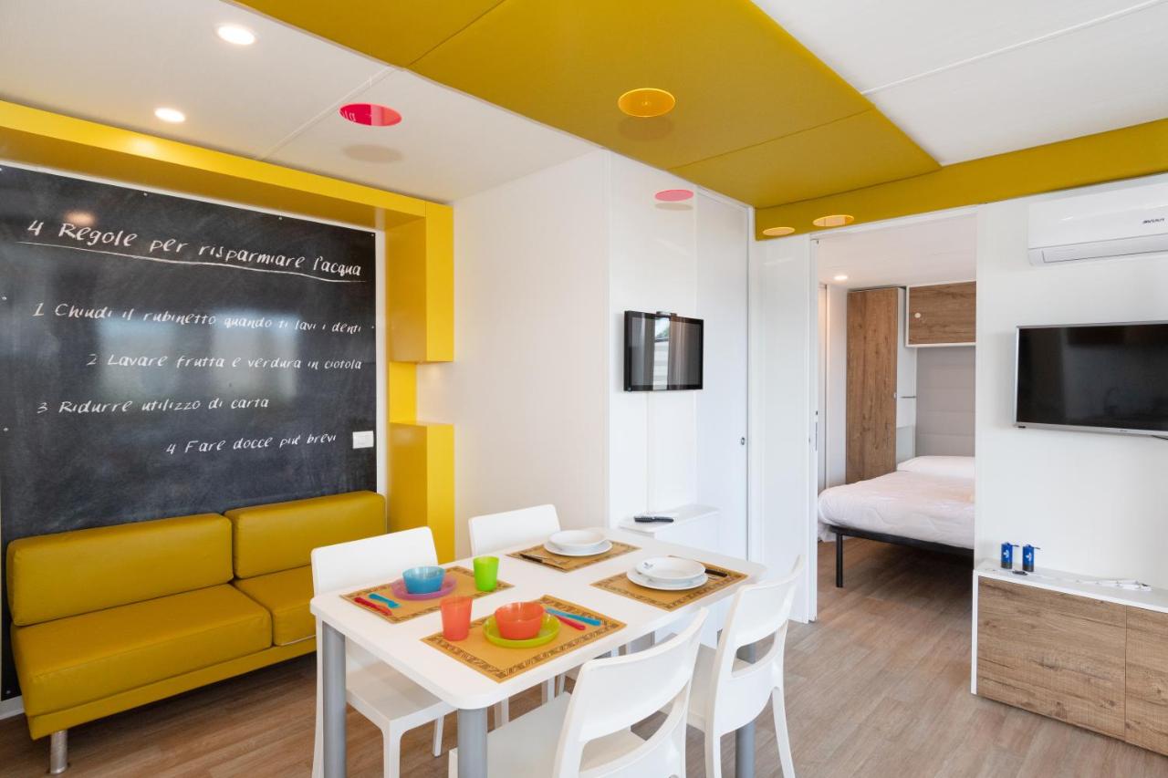 een kamer met een tafel en stoelen en een schoolbord bij Club del Sole Jesolo Family Resort in Lido di Jesolo