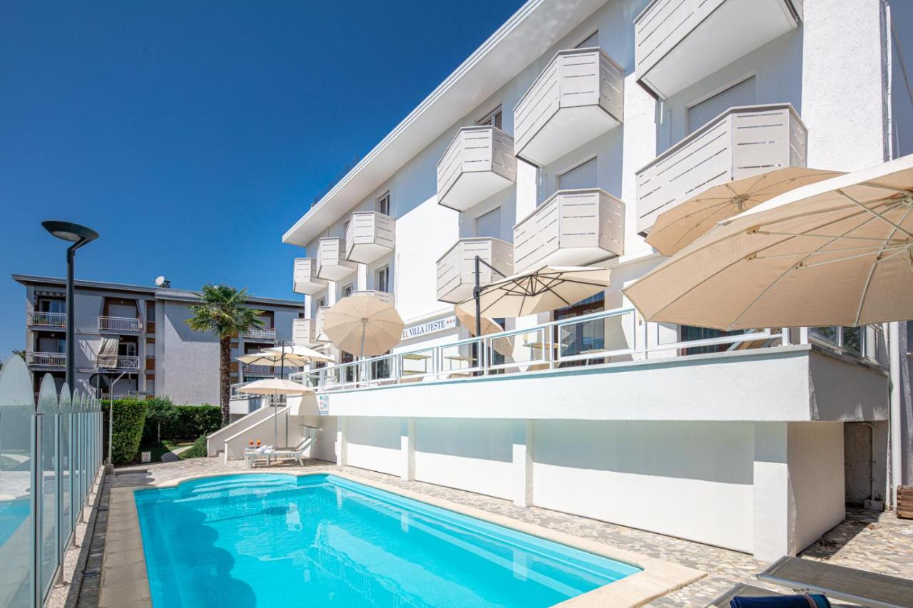 een appartementencomplex met een zwembad en een parasol bij Hotel Villa d'Este in Grado