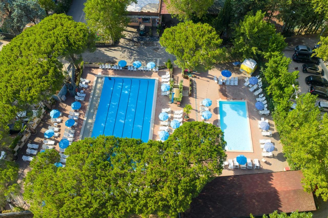 een bovenaanzicht van een zwembad met blauwe parasols bij Camping Village Punta Navaccia in Tuoro sul Trasimeno