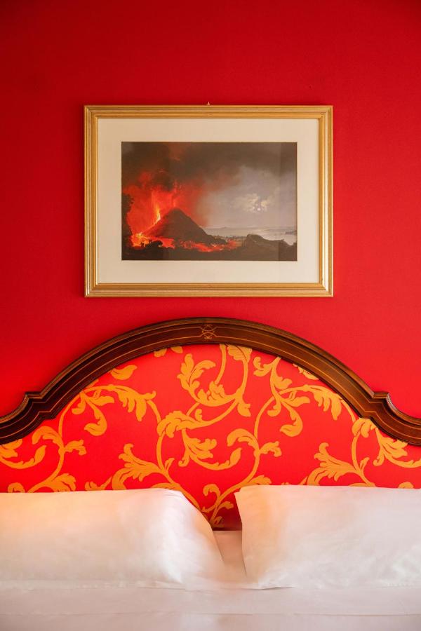 een slaapkamer met een rode muur en een schilderij boven het bed bij Hotel Isabella in Taormina