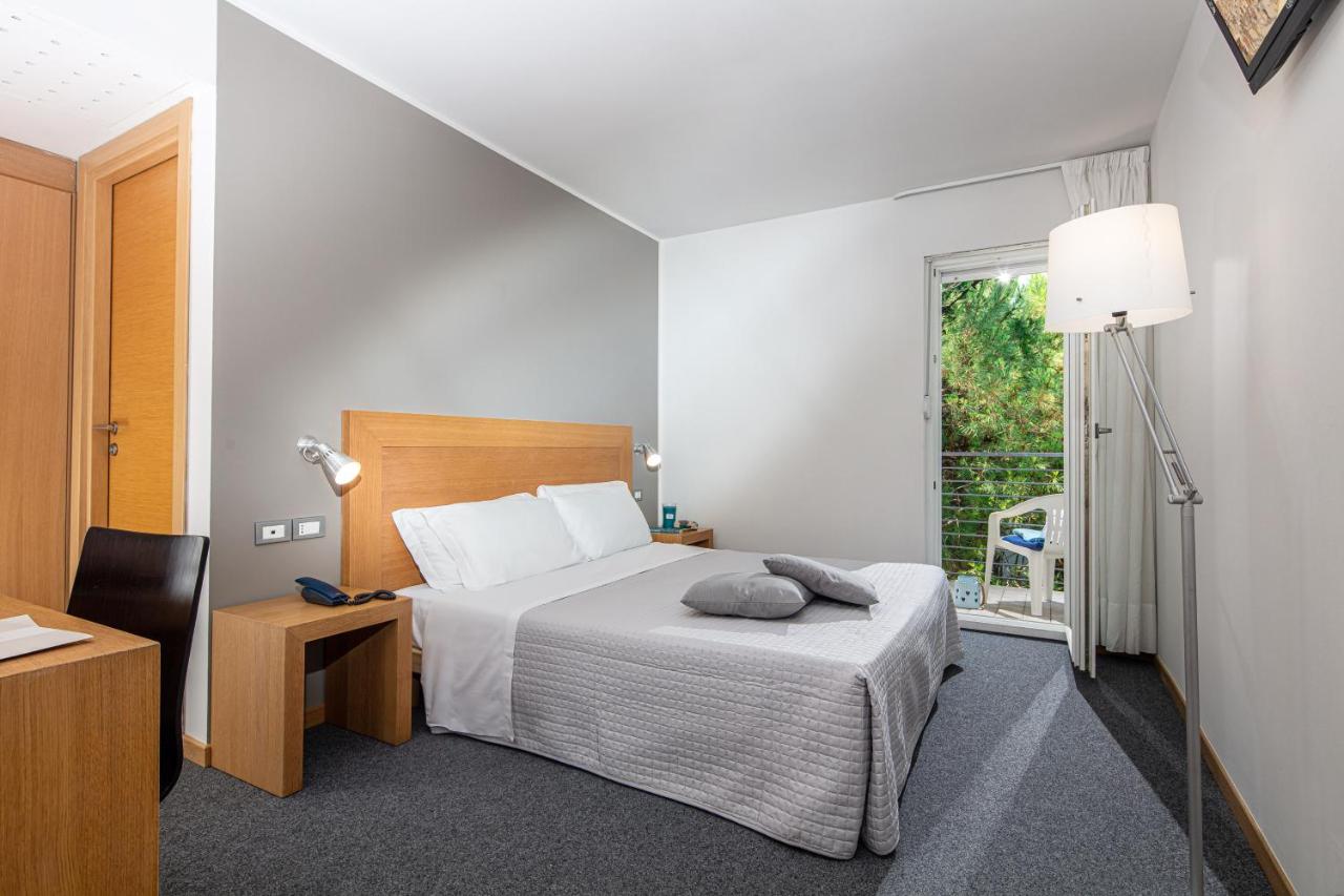een slaapkamer met een bed, een bureau en een raam bij Hotel Martini in Lignano Sabbiadoro