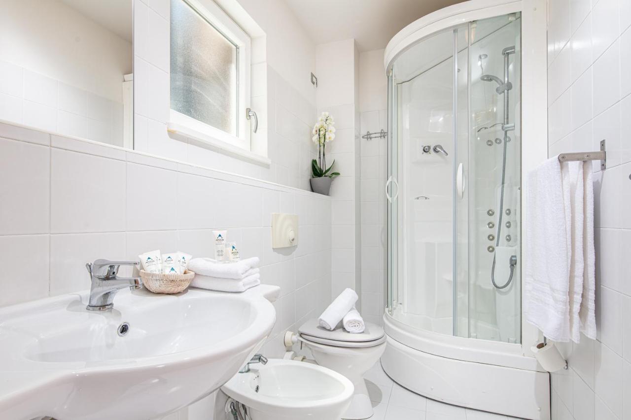 een witte badkamer met een wastafel en een toilet bij Hotel Martini in Lignano Sabbiadoro