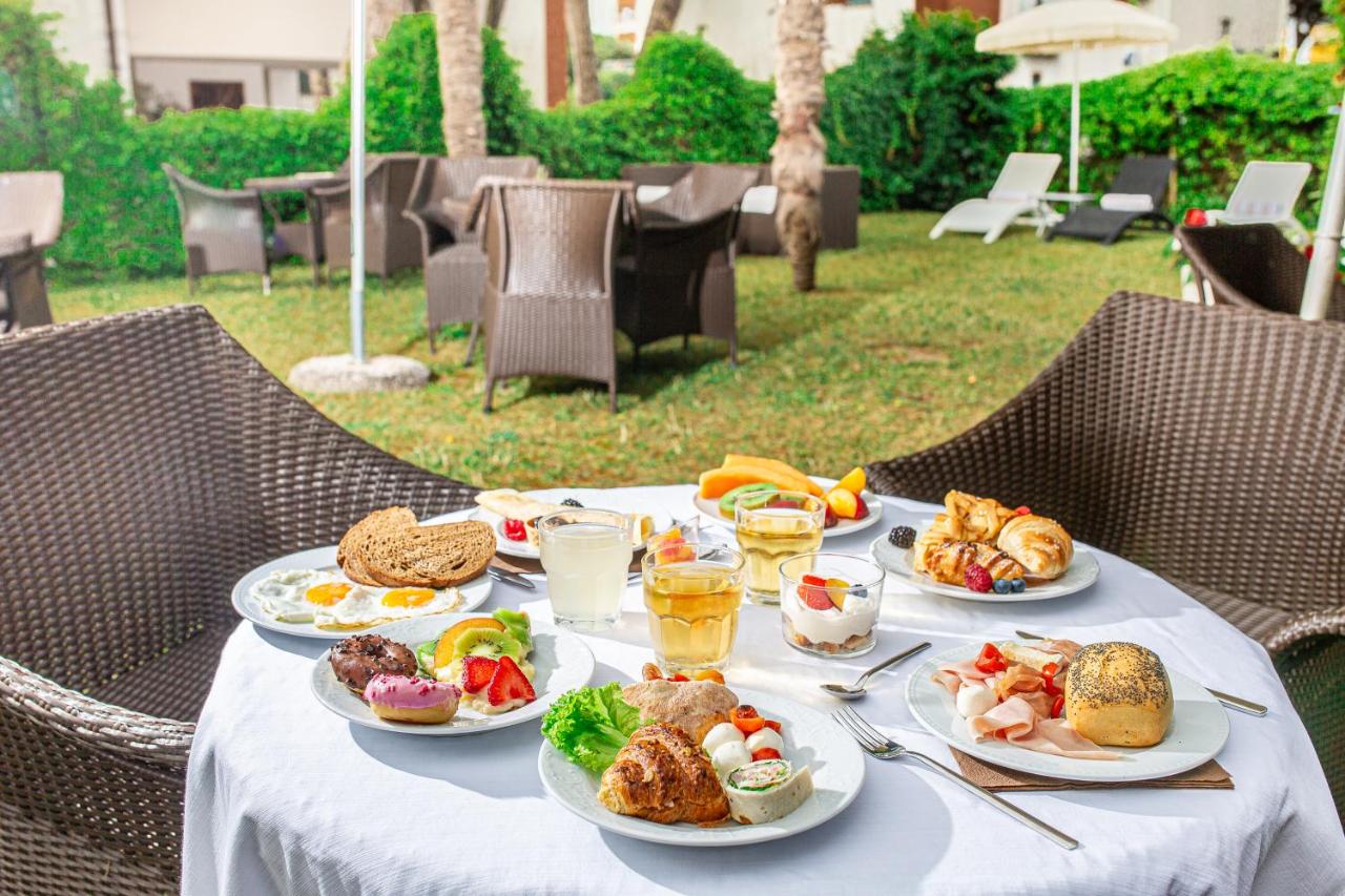 een tafel met borden met eten en drinken erop bij Hotel Martini in Lignano Sabbiadoro