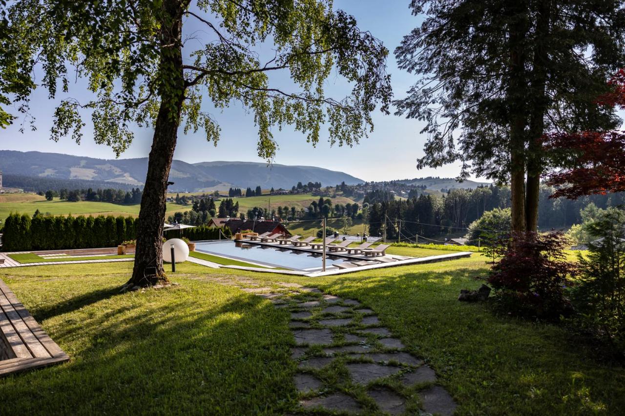 een tuin met een zwembad en bergen op de achtergrond bij Linta Hotel Wellness & Spa in Asiago