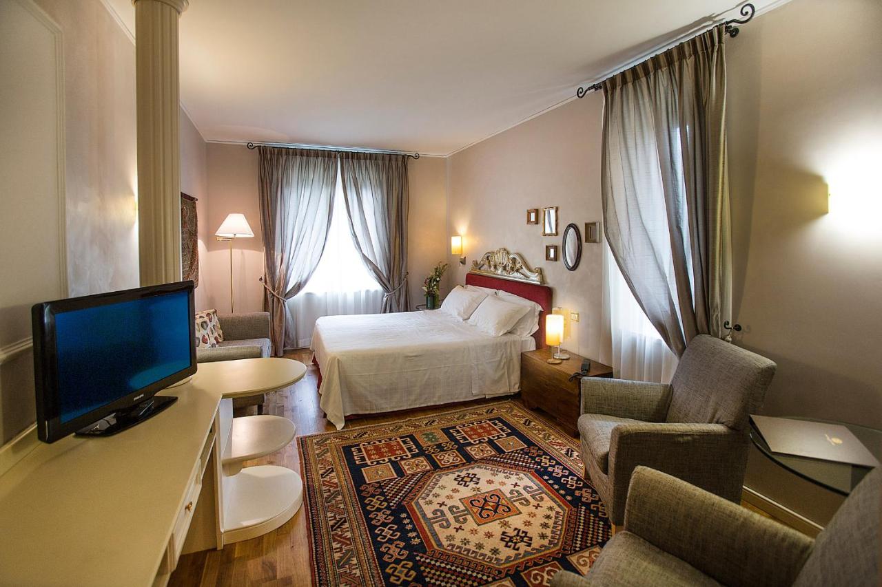 een slaapkamer met een bed en een bureau met een televisie bij Regina Adelaide Hotel & SPA in Garda