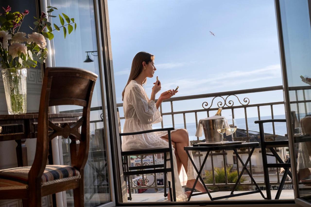 een vrouw zit op een balkon en kijkt uit het raam. bij Palace Hotel in Viareggio