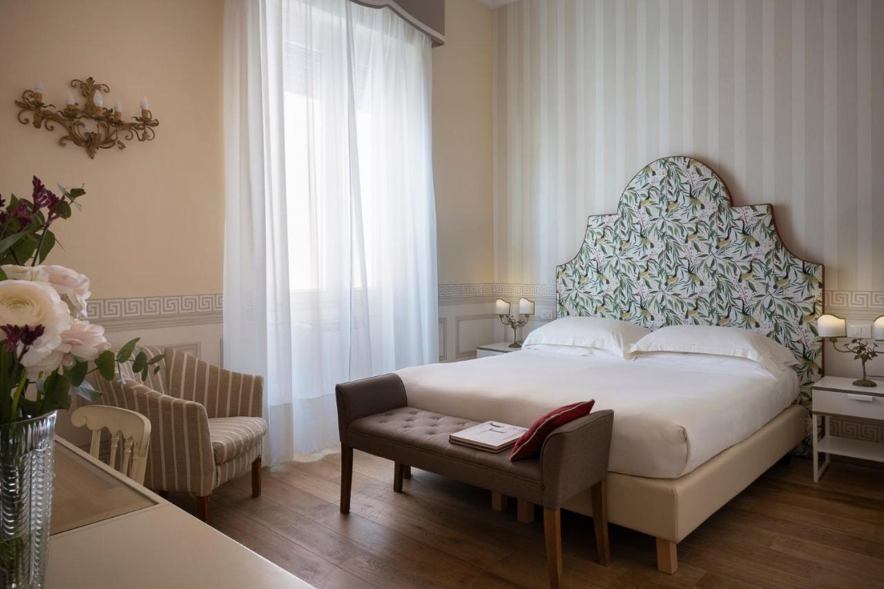 een slaapkamer met een bed, een tafel en een stoel bij Palace Hotel in Viareggio
