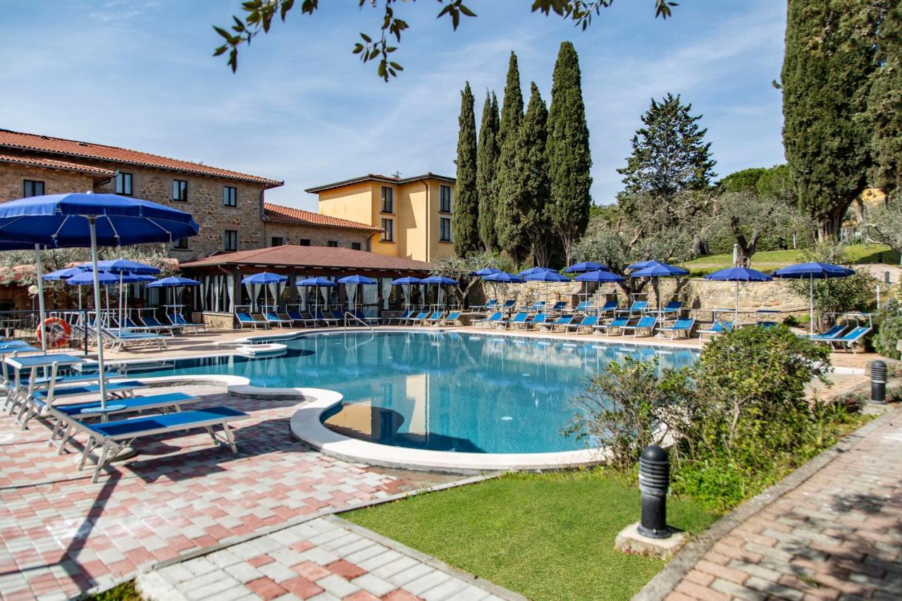 een groot zwembad met blauwe parasols en ligstoelen bij Hotel Villa Paradiso in Passignano sul Trasimeno