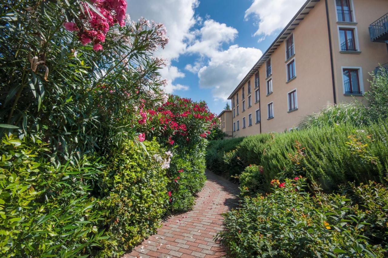 een bakstenen pad voor een gebouw met bloemen bij Hotel Villa Paradiso in Passignano sul Trasimeno