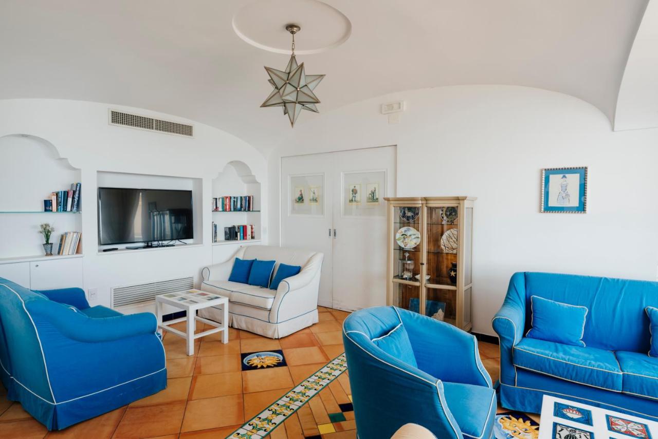 een woonkamer met blauwe stoelen en een tv bij Hotel Cetus in Cetara