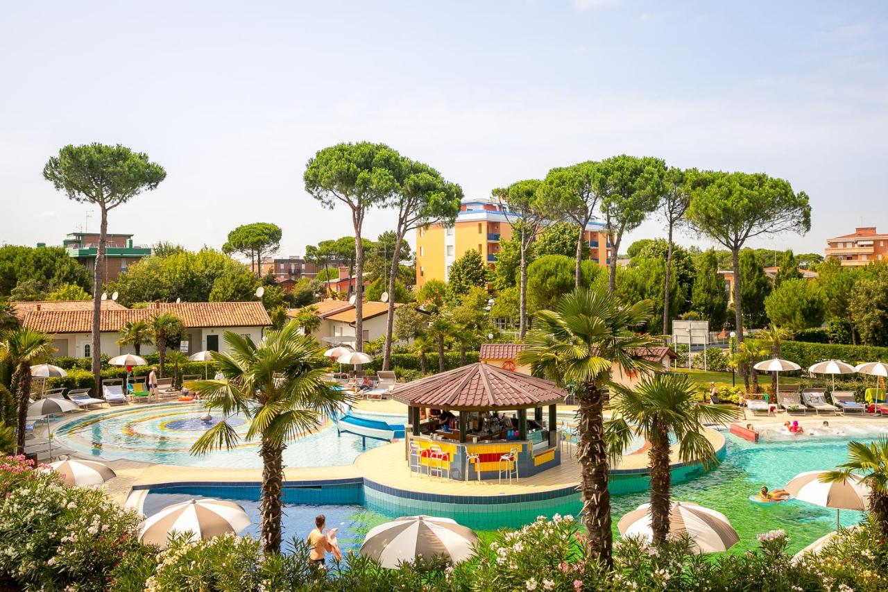 een zwembad bij een resort met palmbomen bij Mediterranee Family Hotel & Spa in Bibione