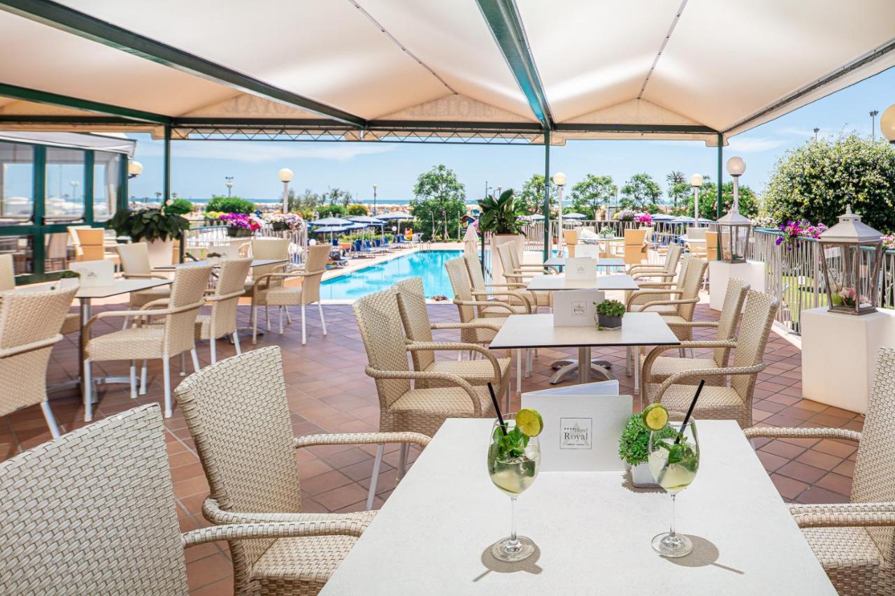 een restaurant met tafels en stoelen en een zwembad bij Hotel Royal in Bibione