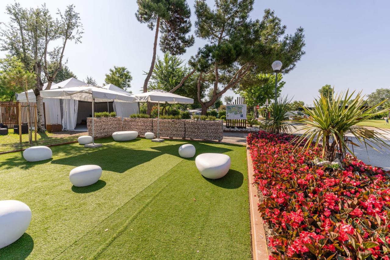 een tuin met witte stoelen en rode bloemen bij Club del Sole Spina Family Collection in Lido di Spina