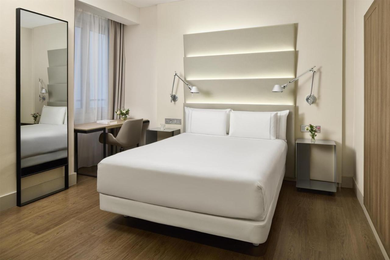 een slaapkamer met een groot wit bed en een bureau bij NH Sants Barcelona in Barcelona
