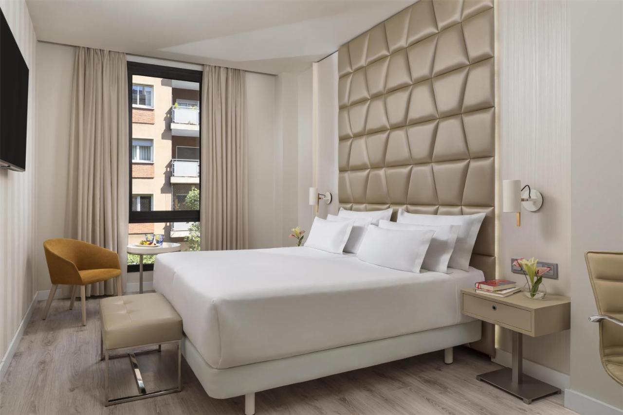 een slaapkamer met een groot wit bed en een raam bij NH Collection Barcelona Podium in Barcelona