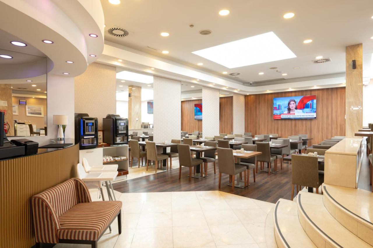 een restaurant met tafels en stoelen en een tv bij THE Hotel MASA Almirante LISBON Stylish in Lissabon