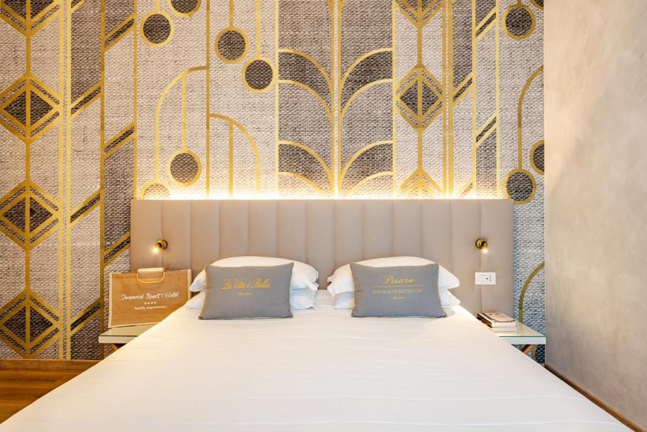 een slaapkamer met een bed met twee blauwe kussens bij UNAHOTELS Imperial Sport Hotel in Pesaro
