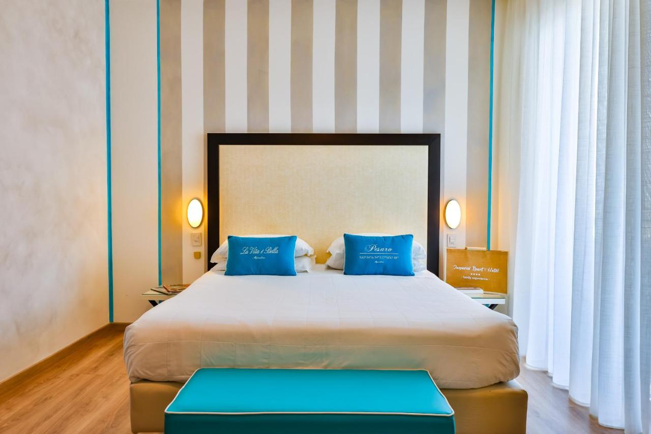 een slaapkamer met een groot bed met blauwe kussens bij UNAHOTELS Imperial Sport Hotel in Pesaro