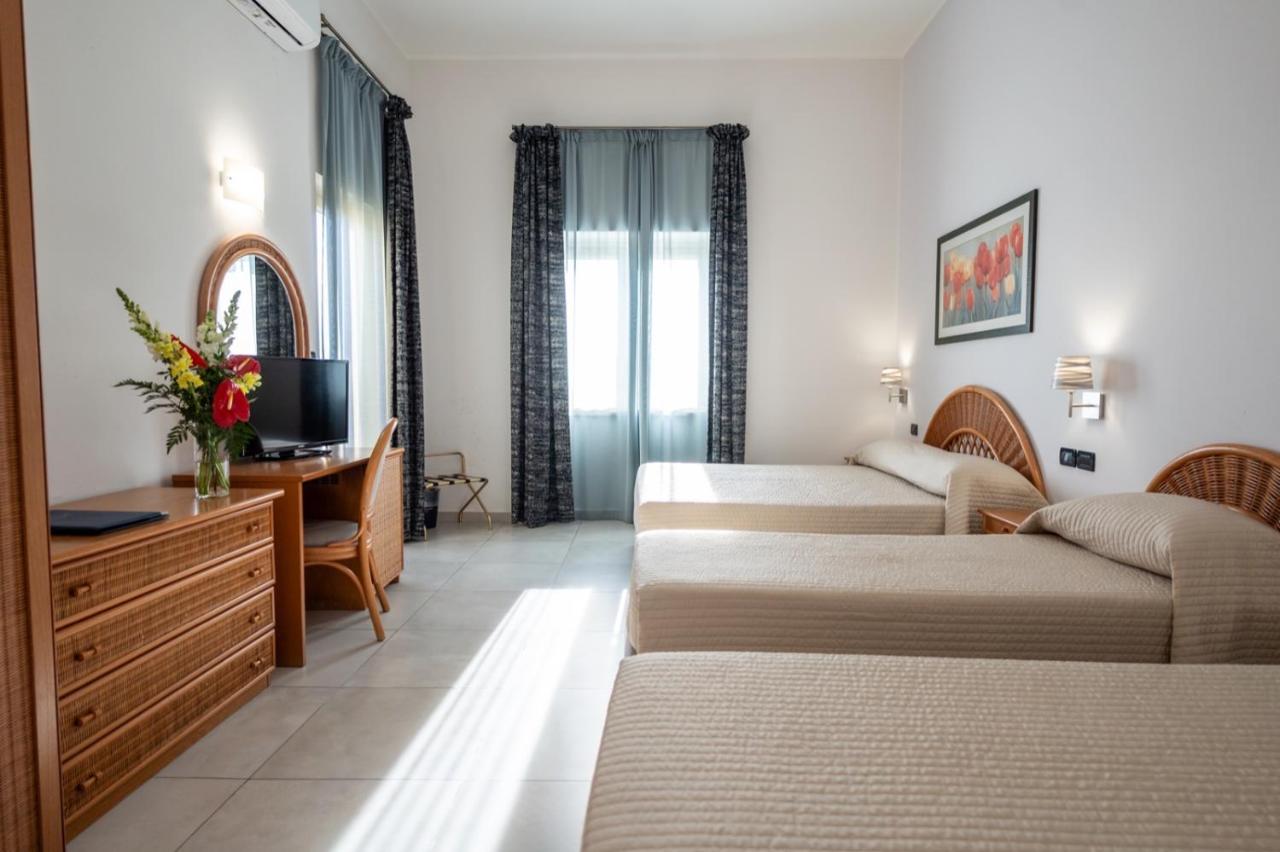 een hotelkamer met drie bedden en een bureau bij Hotel Corallo in Taormina