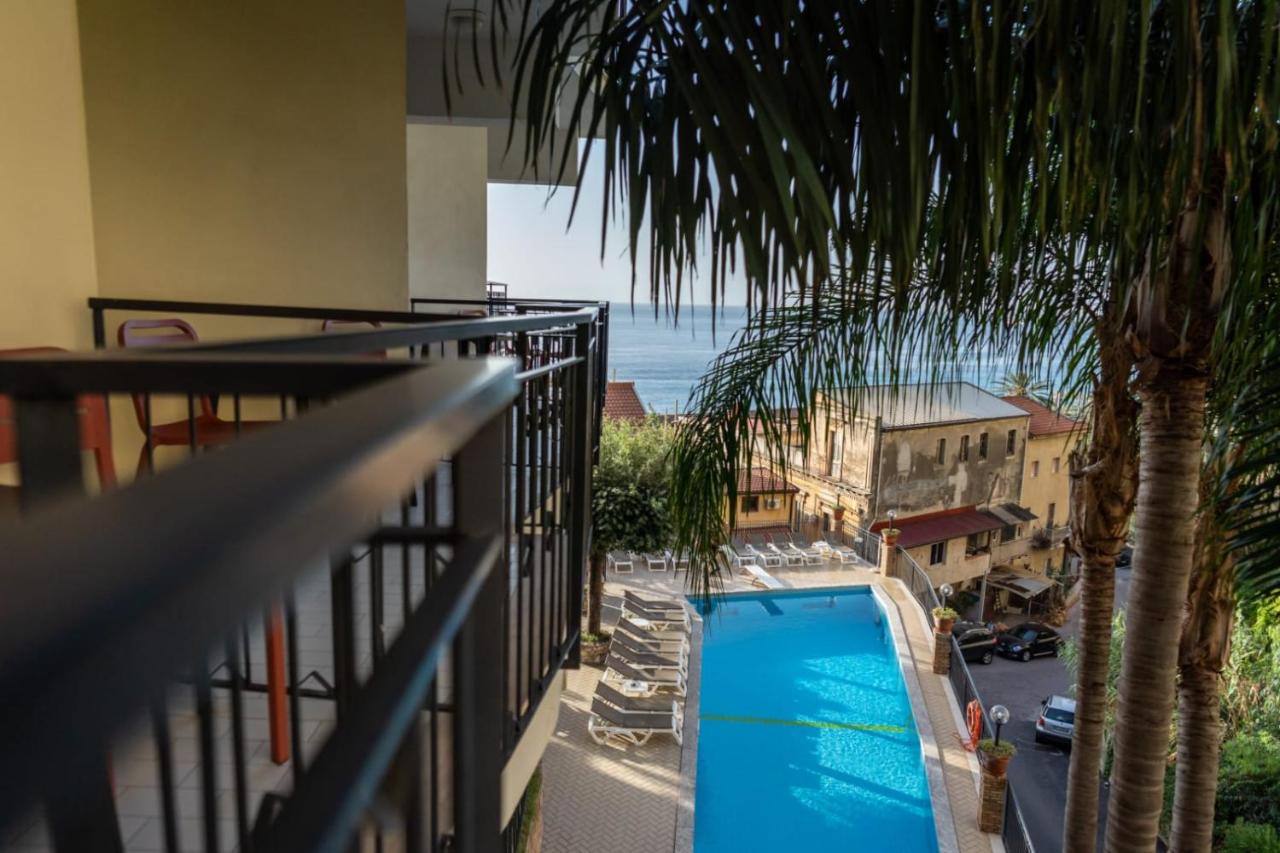 een balkon met een palmboom en een zwembad bij Hotel Corallo in Taormina