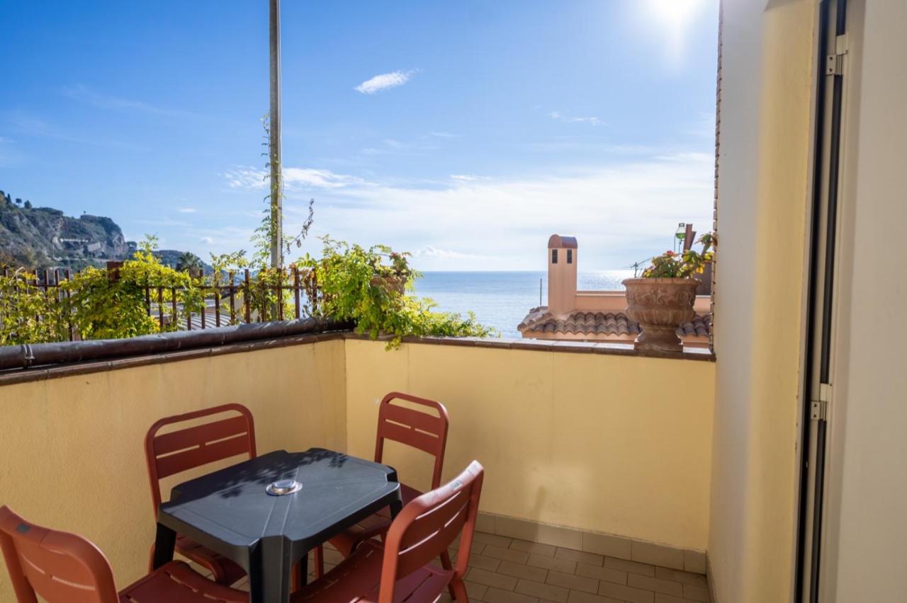Een tafel en stoelen op een balkon met uitzicht op de oceaan. bij Hotel Corallo in Taormina