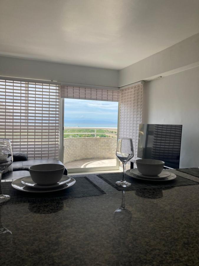 een eetkamer met een tafel met glazen en een raam bij Apartamento vista al mar in Porlamar