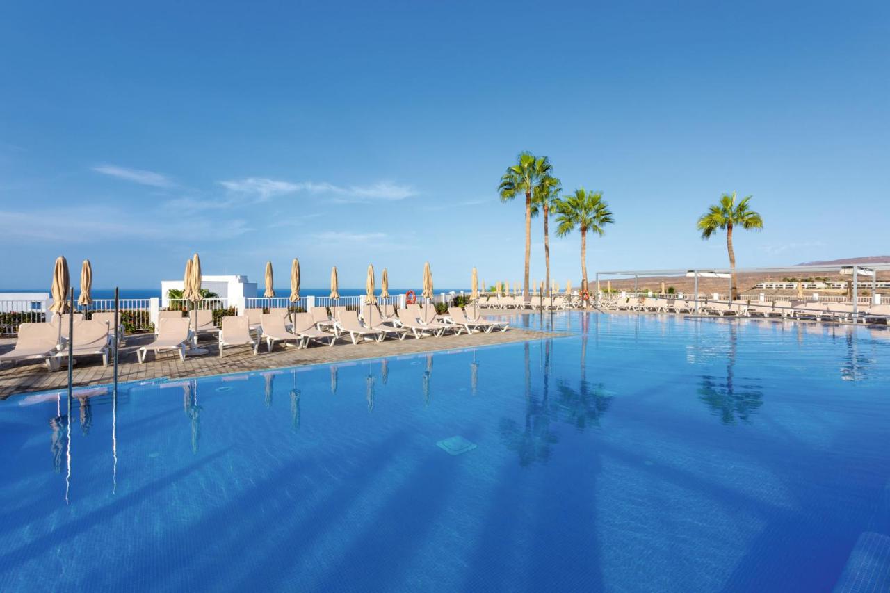 een groot zwembad met ligstoelen en palmbomen bij Hotel Riu Vistamar Gran Canaria - All Inclusive in Puerto Rico de Gran