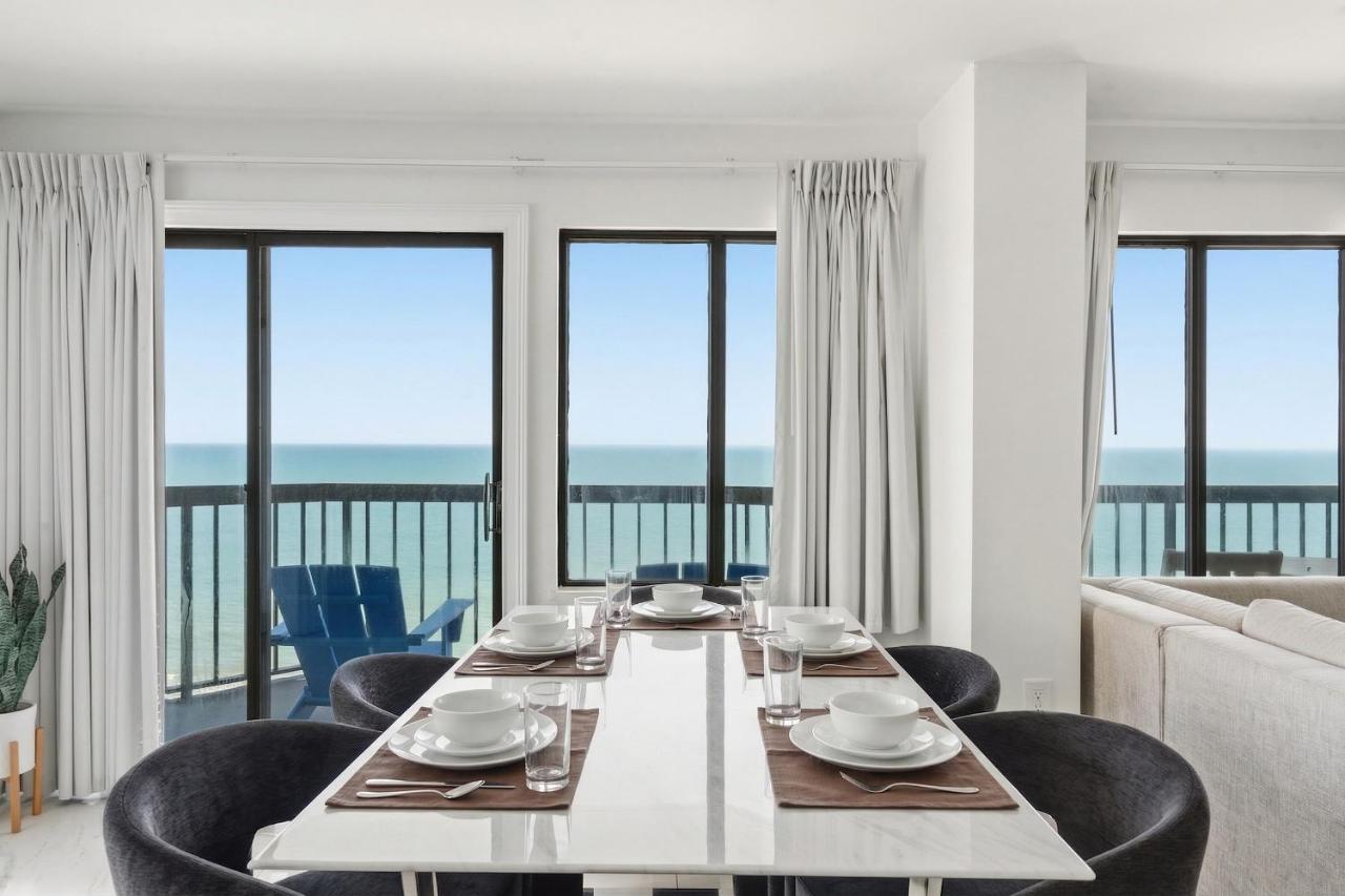 een eetkamer met een tafel en stoelen en uitzicht op de oceaan bij Grande Beach Resort in Myrtle Beach