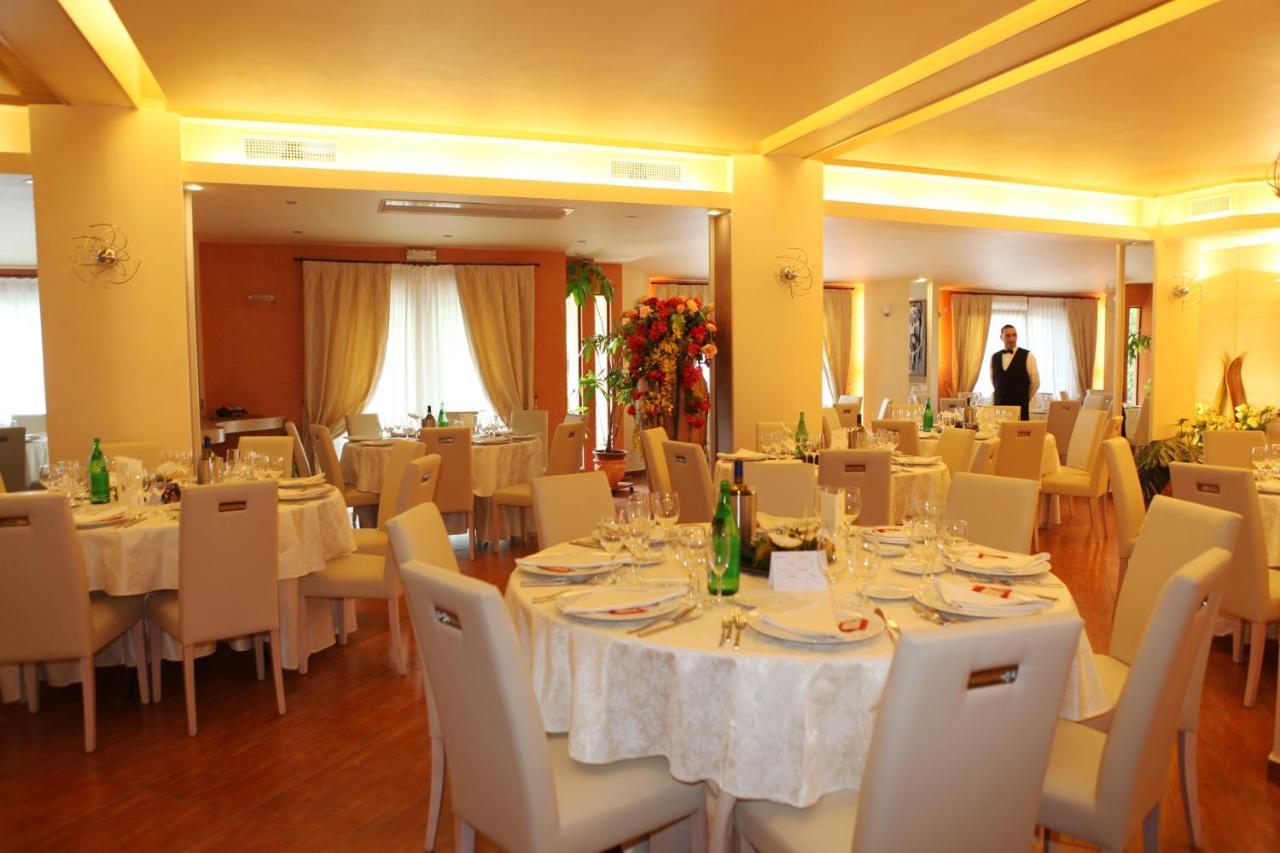 een restaurant met witte tafels en witte stoelen en een man bij Hotel Villaggio Old River in Capo Vaticano +58 foto's