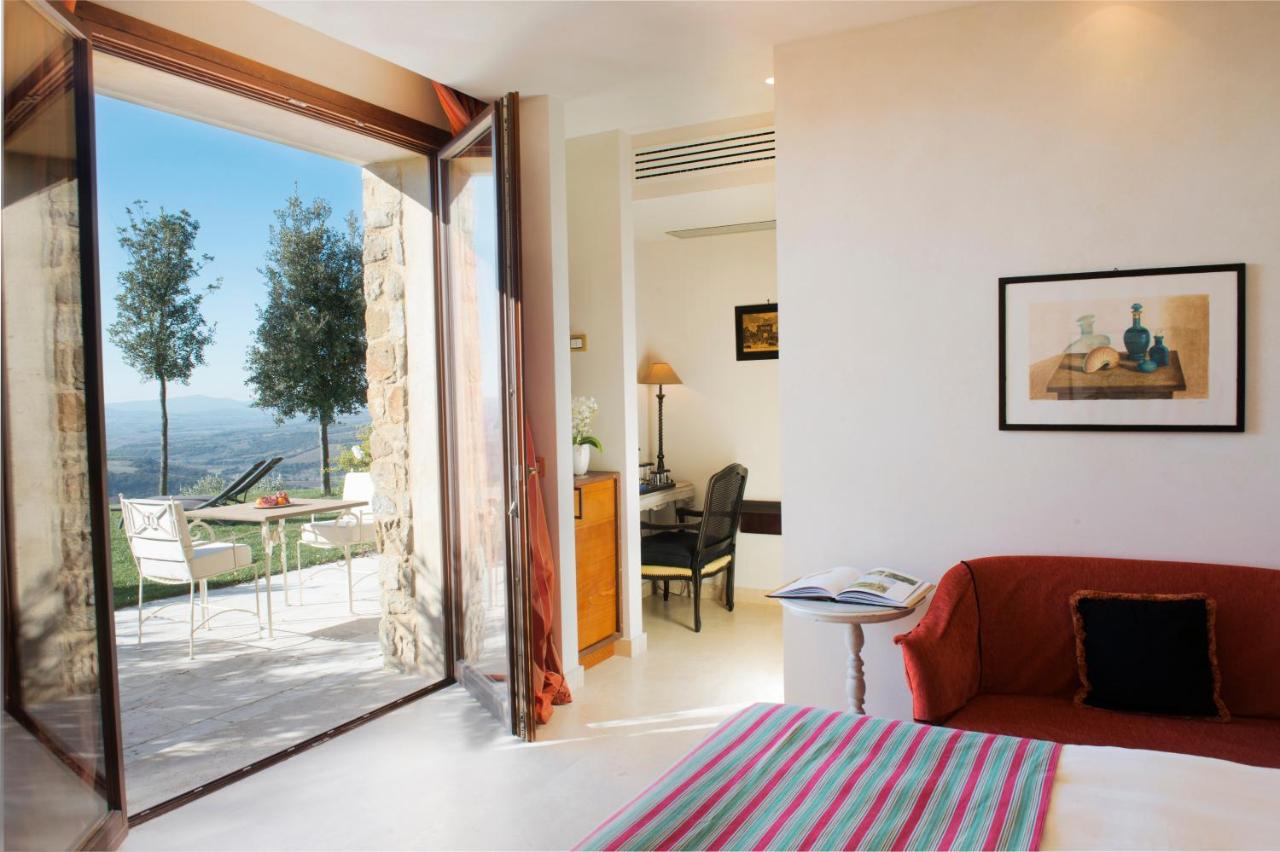 een woonkamer met een rode bank en een balkon bij Castello di Velona Resort, Thermal SPA & Winery in Montalcino