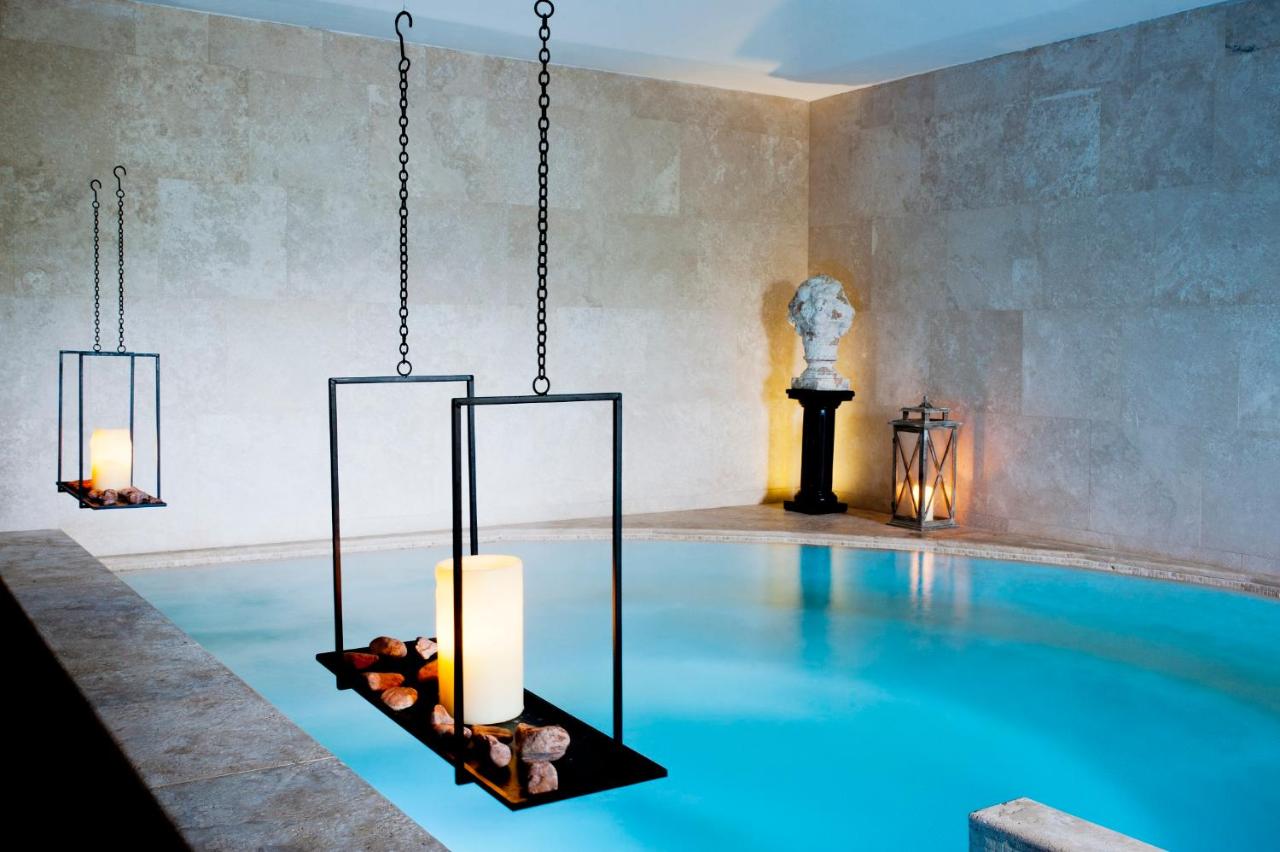 een kamer met een zwembad met een kroonluchter bij Castello di Velona Resort, Thermal SPA & Winery in Montalcino