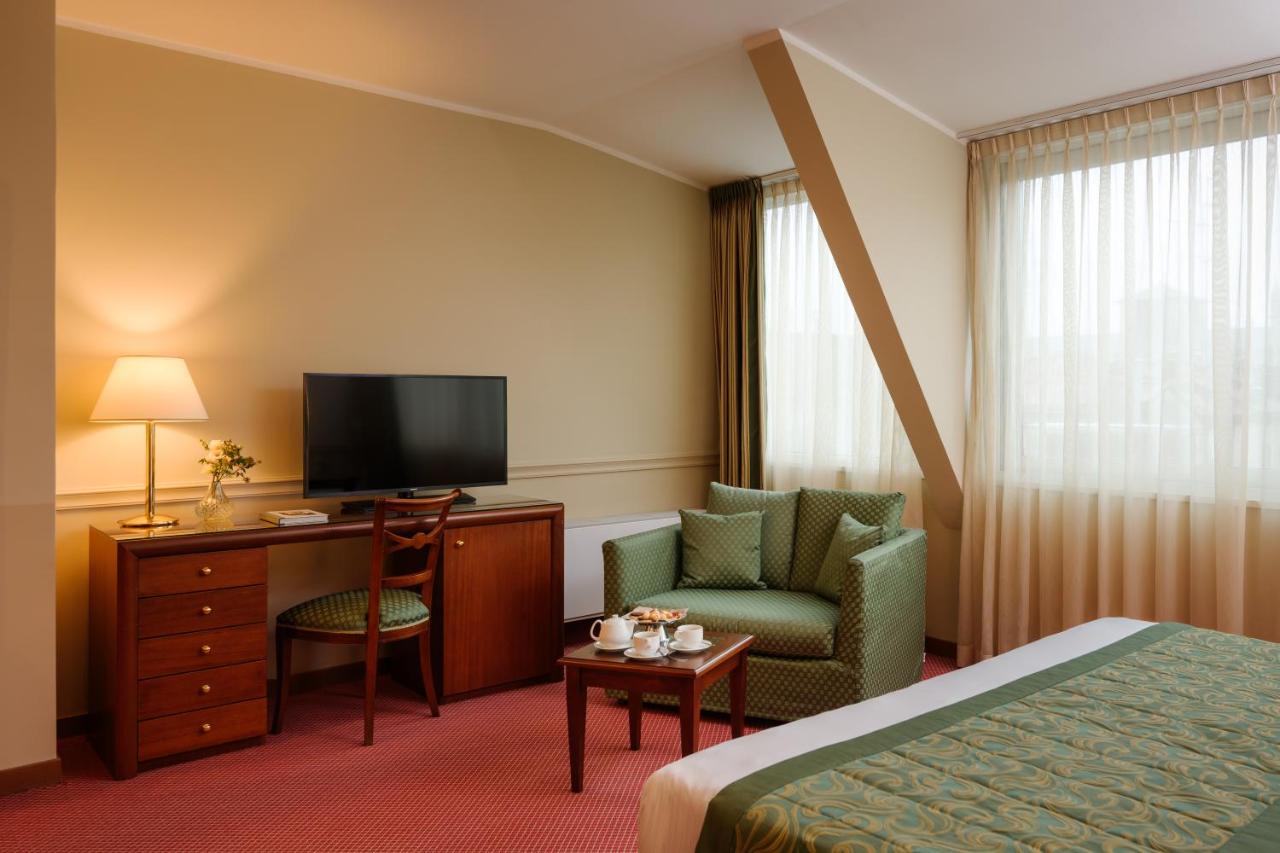 een hotelkamer met een bed, een stoel en een televisie bij Hotel Barchetta Excelsior in Como