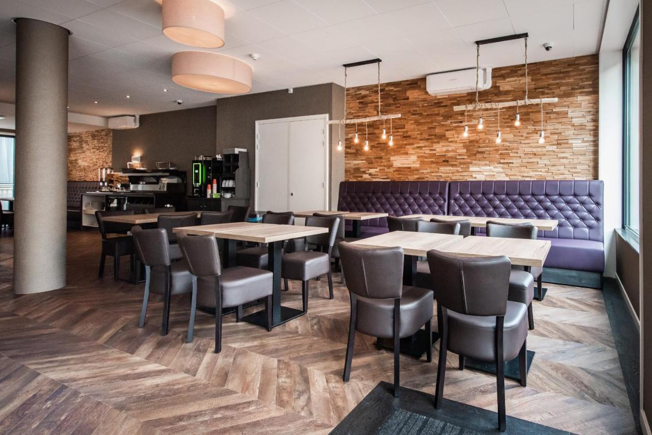 een restaurant met houten tafels en stoelen en een bakstenen muur bij Melrose Hotel in Amsterdam