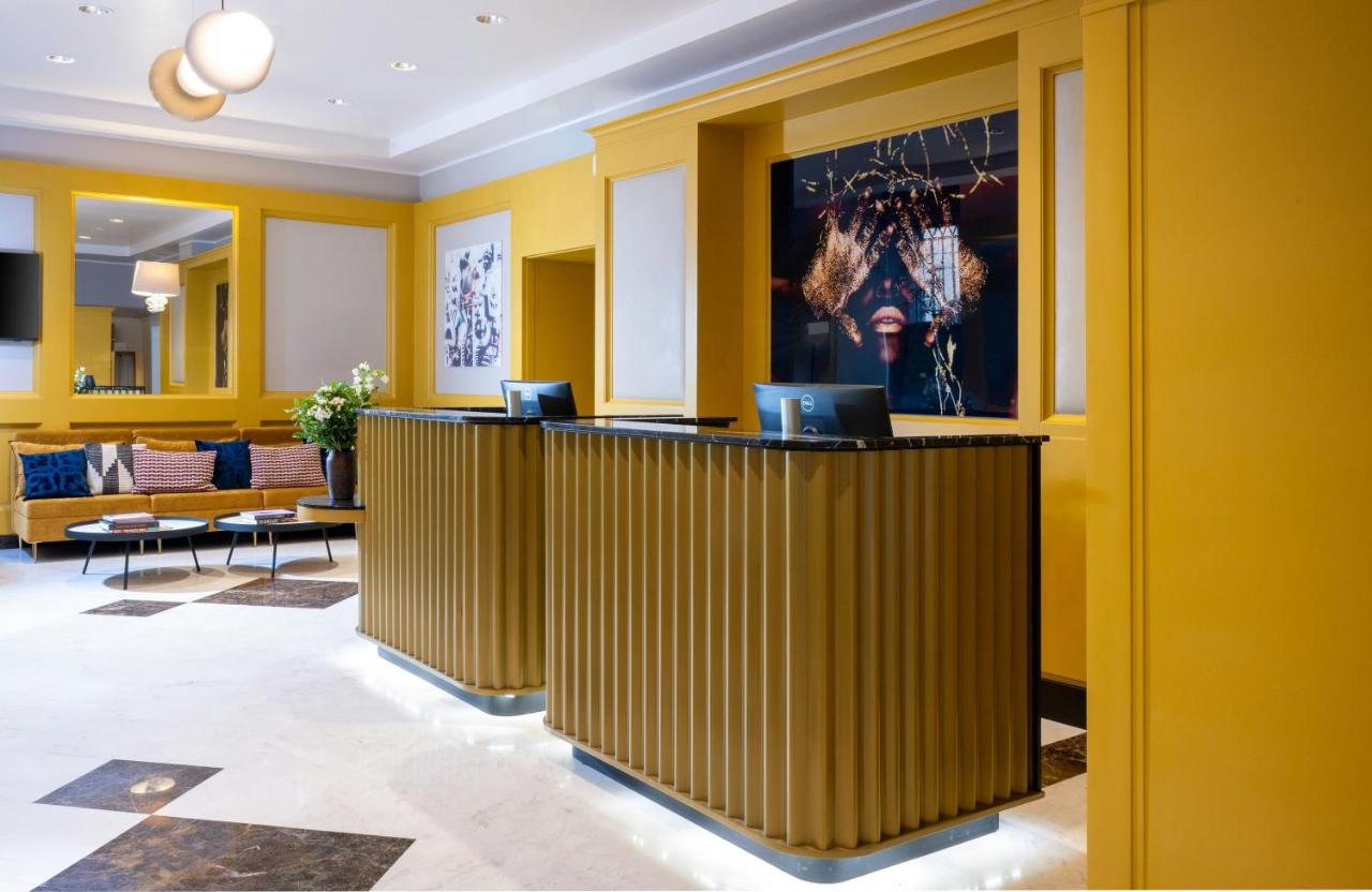 De lobby van een hotel met gele muren en tafels. bij Leonardo Boutique Hotel Rome Monti in Rome