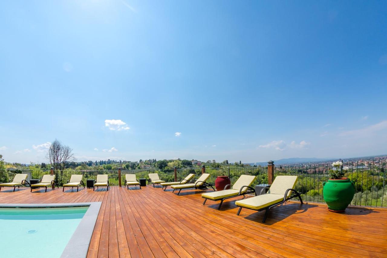een rij ligstoelen op een terras naast een zwembad bij Villa Tolomei Hotel & Resort in Florence