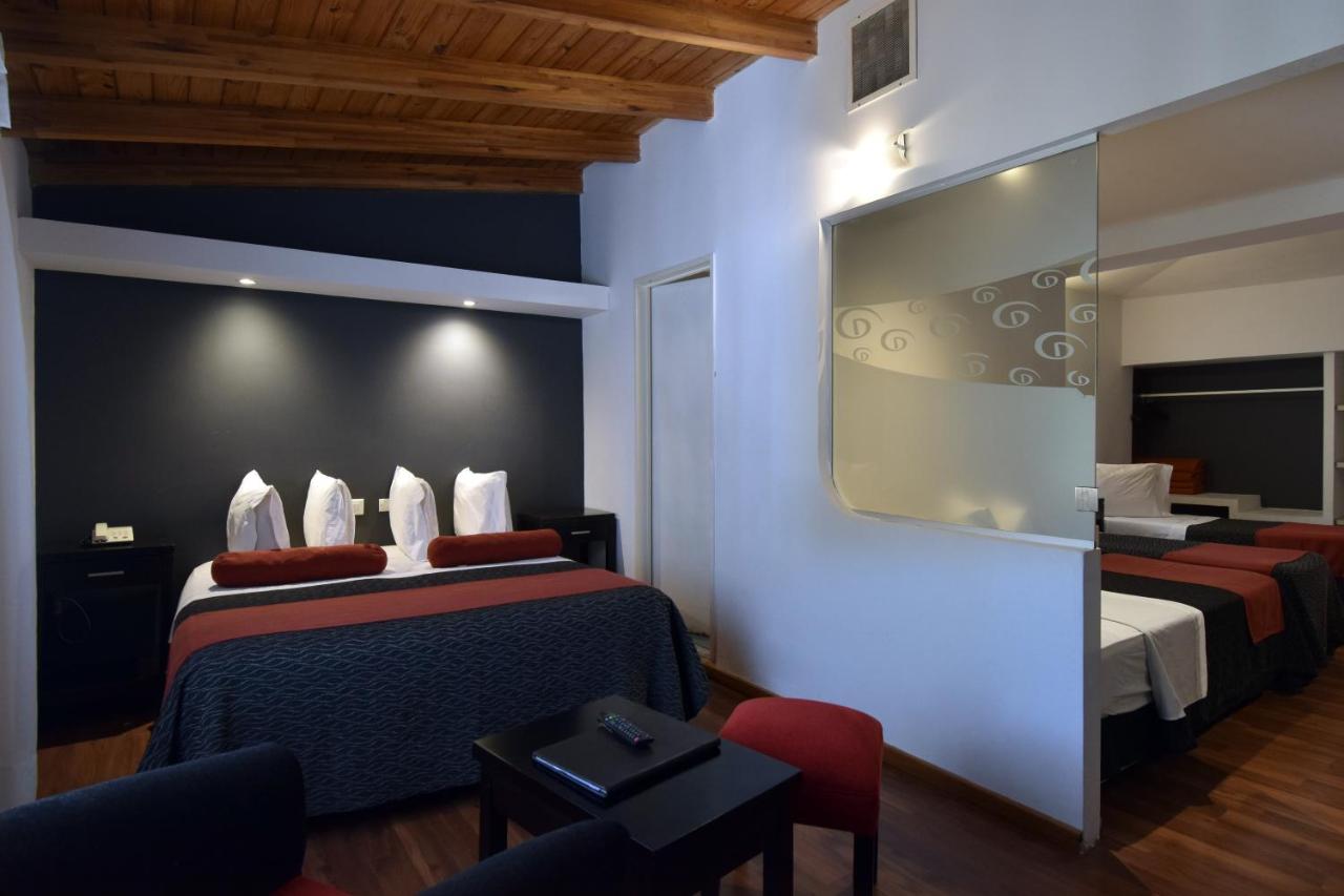 een hotelkamer met twee bedden en een spiegel bij Piazza Hotel in Villa Carlos Paz