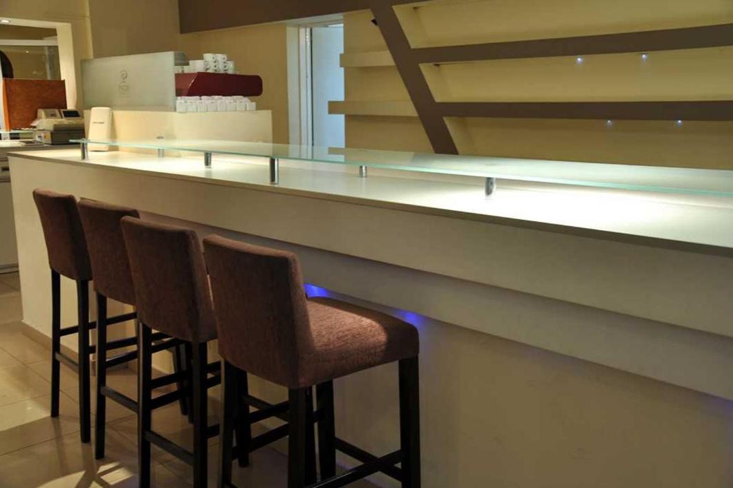 een bar met vier stoelen aan een toonbank in een keuken bij Piazza Hotel in Villa Carlos Paz