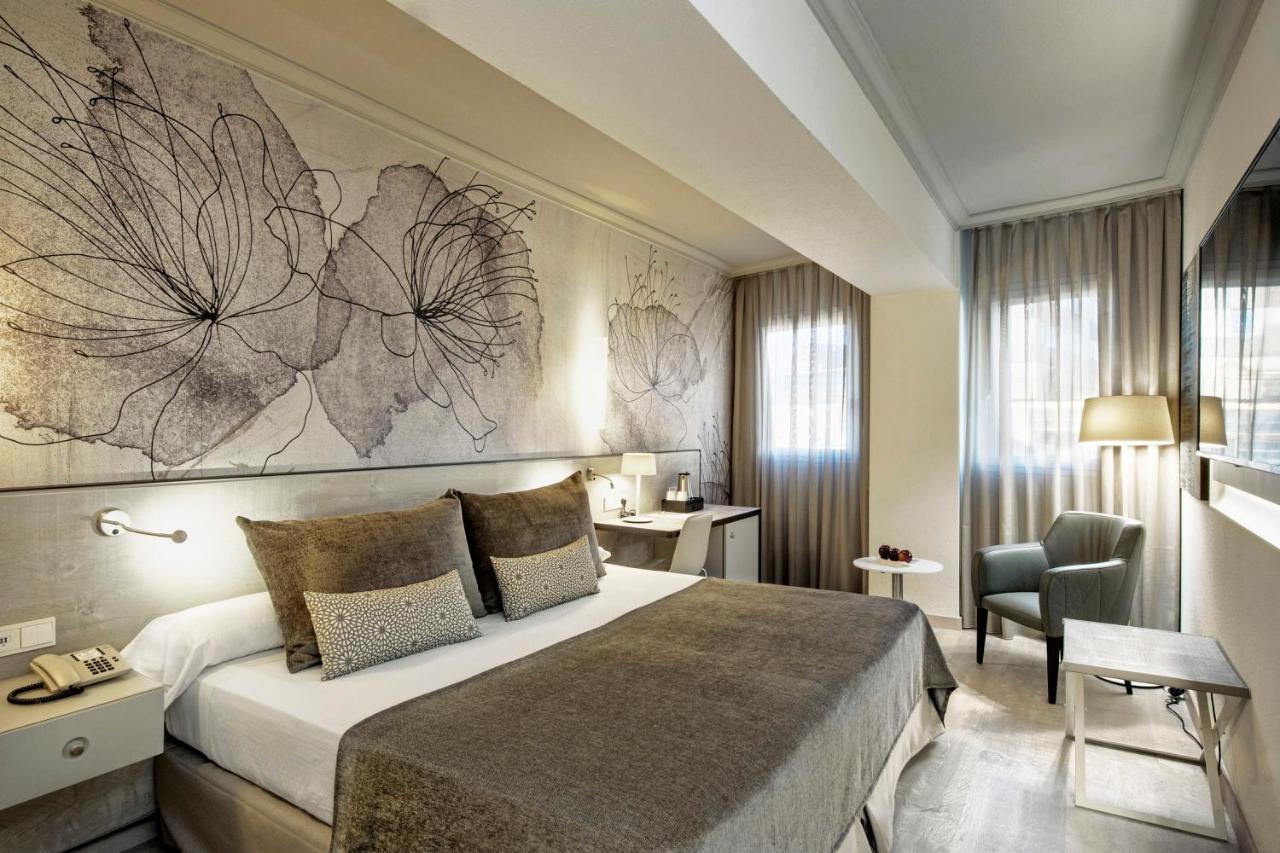 een hotelkamer met een groot bed en een stoel bij Sallés Hotel Pere IV in Barcelona