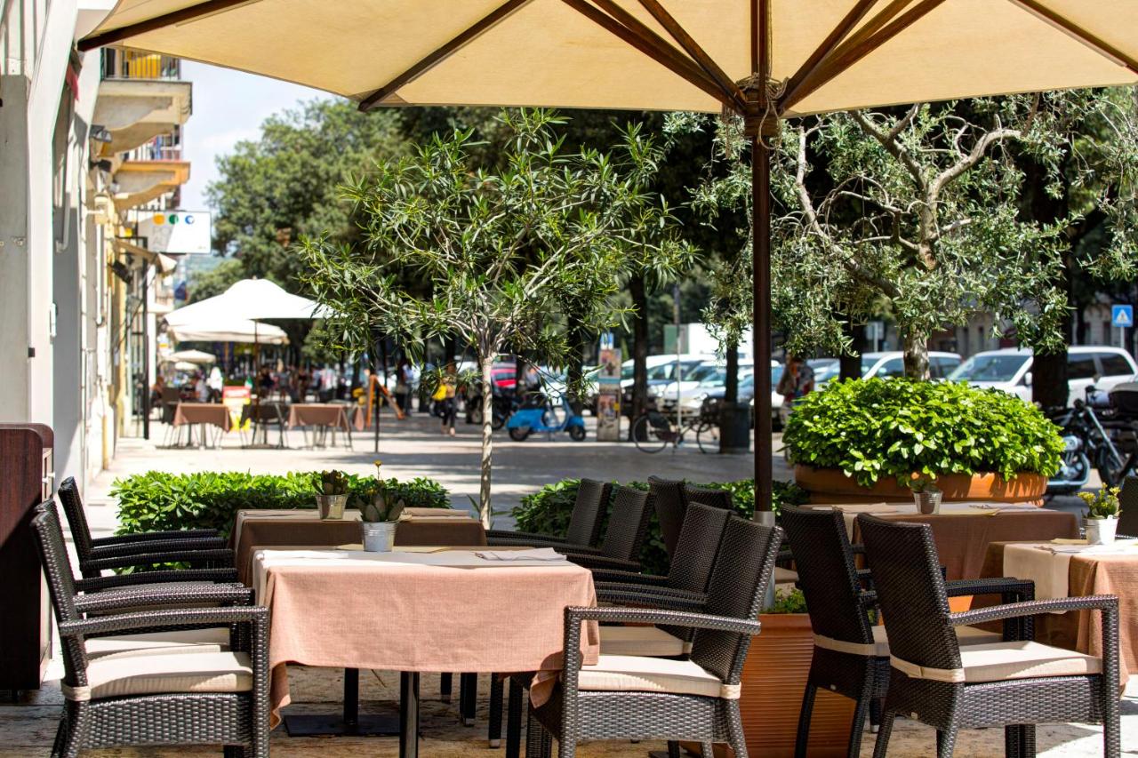 een buitenrestaurant met tafels en stoelen en een parasol bij Ferretti Hotel Firenze in Verona