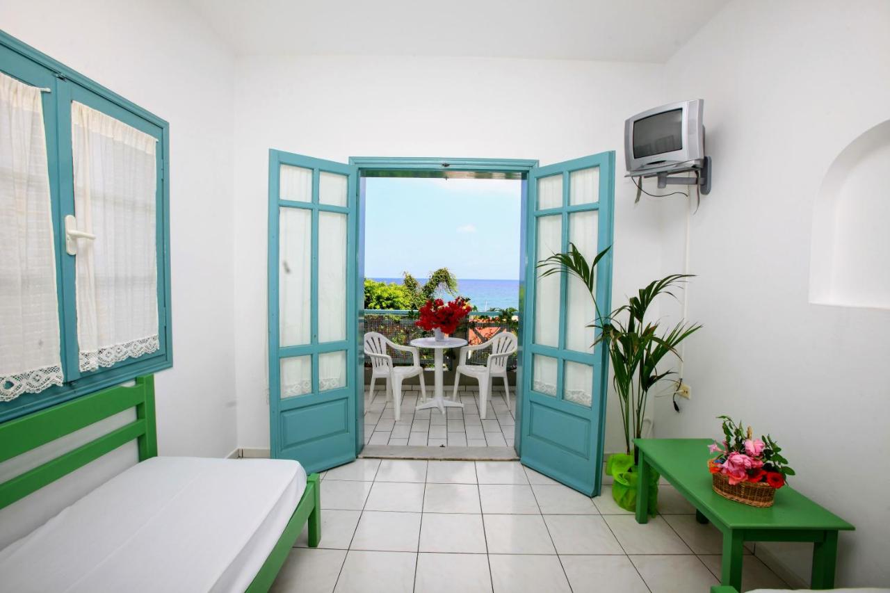 een kamer met een deur die uitkomt op een balkon met een tafel bij Anatoli Apartments in Chersonissos