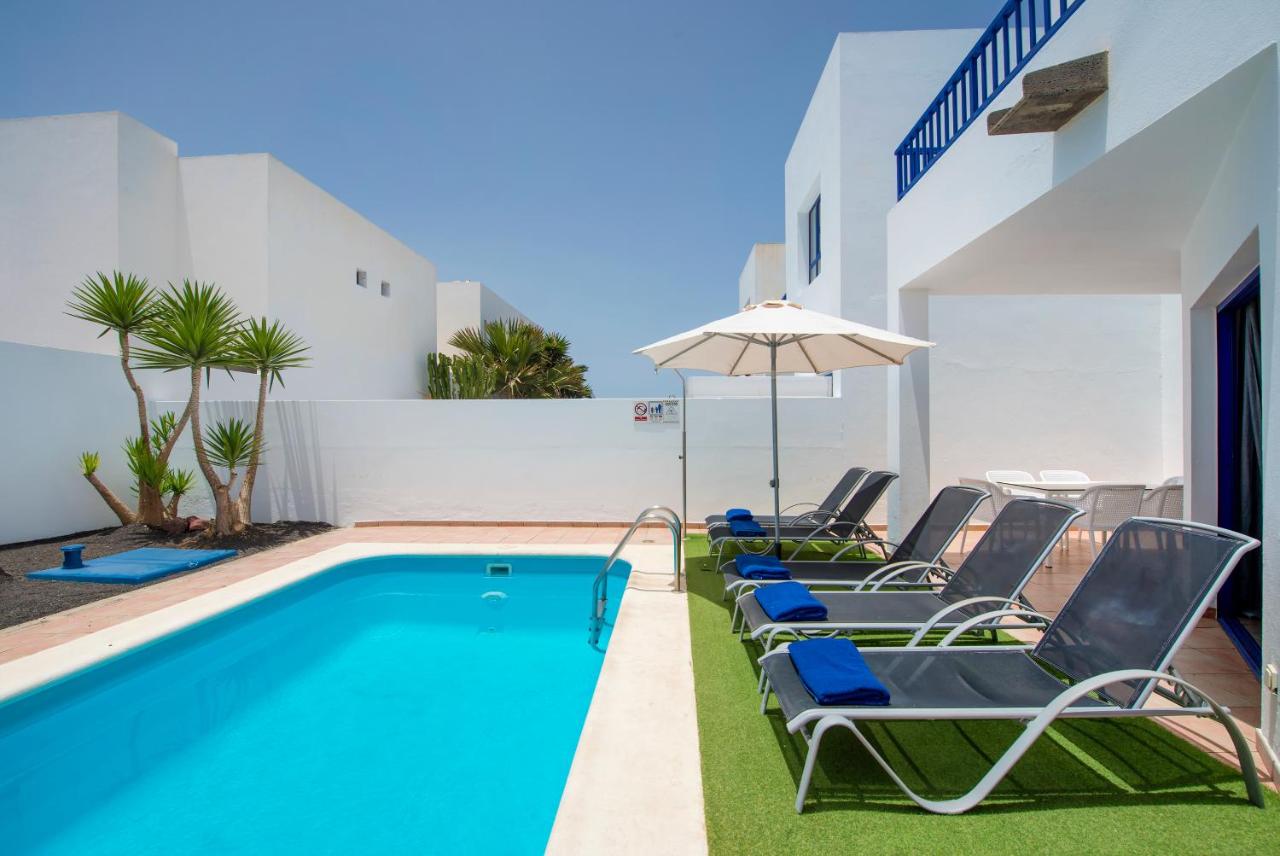een zwembad met ligstoelen en een parasol bij Villas Puerto Rubicon in Playa Blanca