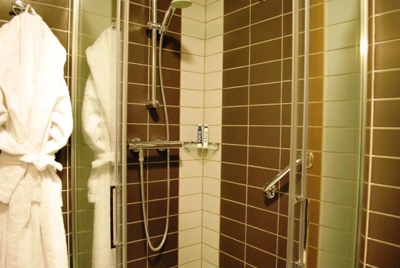 een douche in een badkamer met bruine en groene tegels bij Idea Hotel Plus Savona in Savona