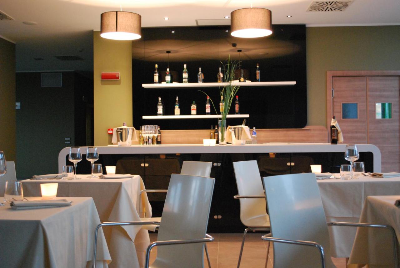 een restaurant met witte tafels en stoelen en een bar bij Idea Hotel Plus Savona in Savona