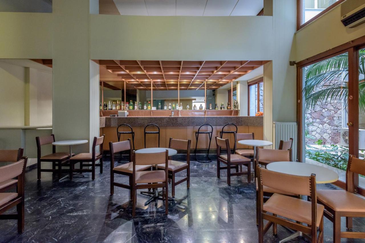 een eetkamer met tafels en stoelen en een bar bij El Greco Hotel in Heraklion