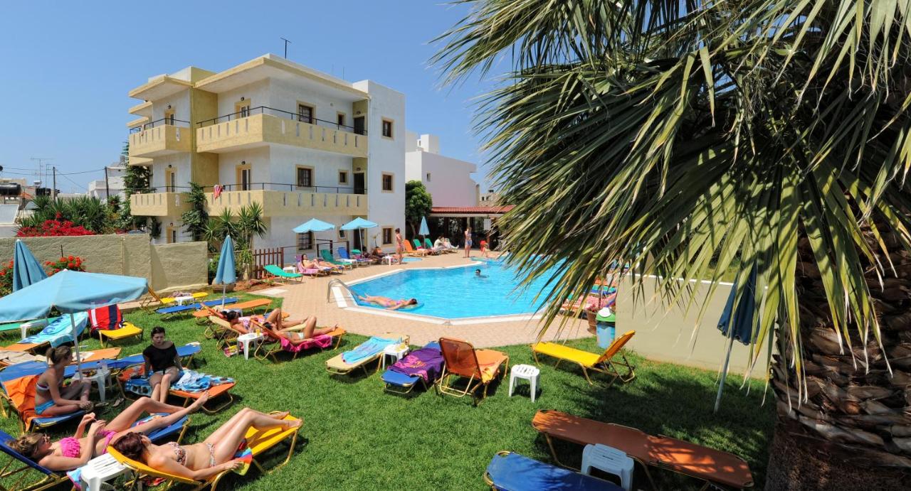 een groep mensen die in tuinstoelen bij een zwembad liggen bij Stelios Residence Apartments in Malia