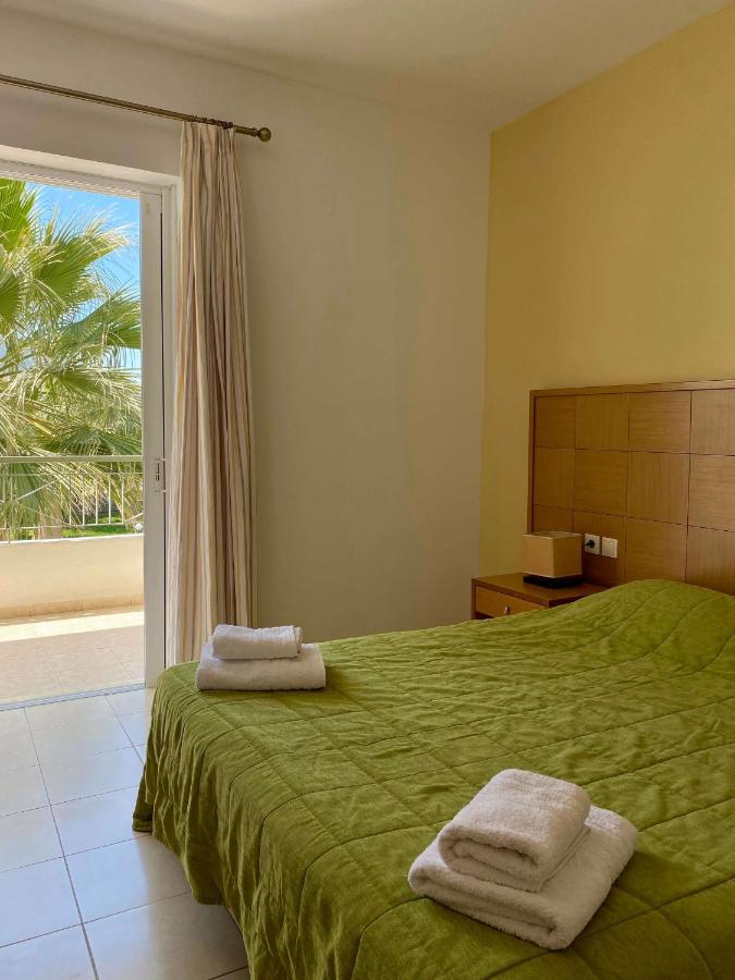 een slaapkamer met een groen bed waarop handdoeken liggen bij Manolis Apartments plakias in Plakias