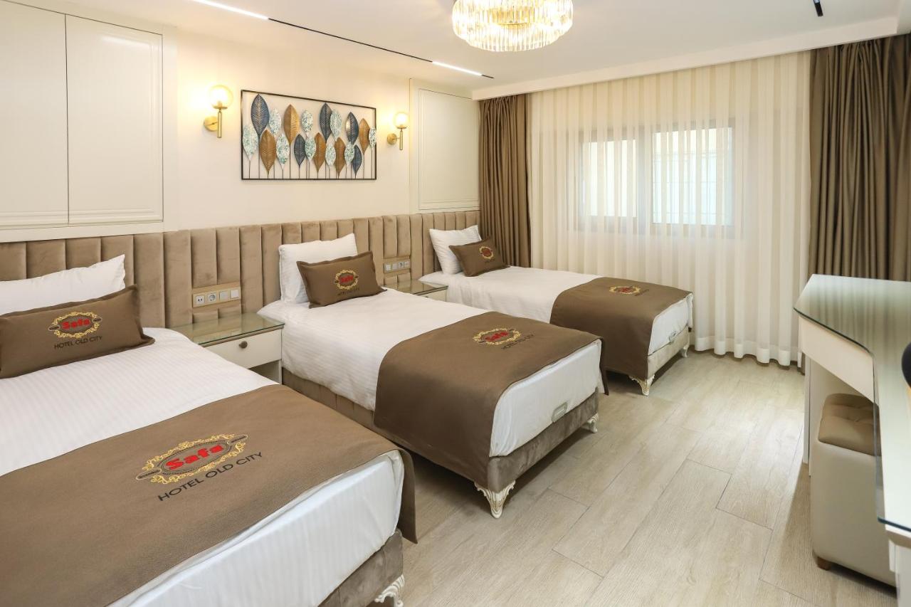een hotelkamer met drie bedden en een kroonluchter bij Safa Hotel Old City in Istanbul
